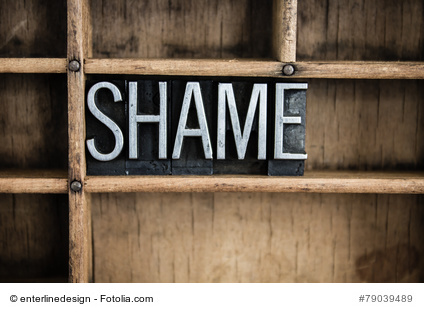 The word "SHAME" written in vintage metal letterpress type in a wooden drawer with dividers.